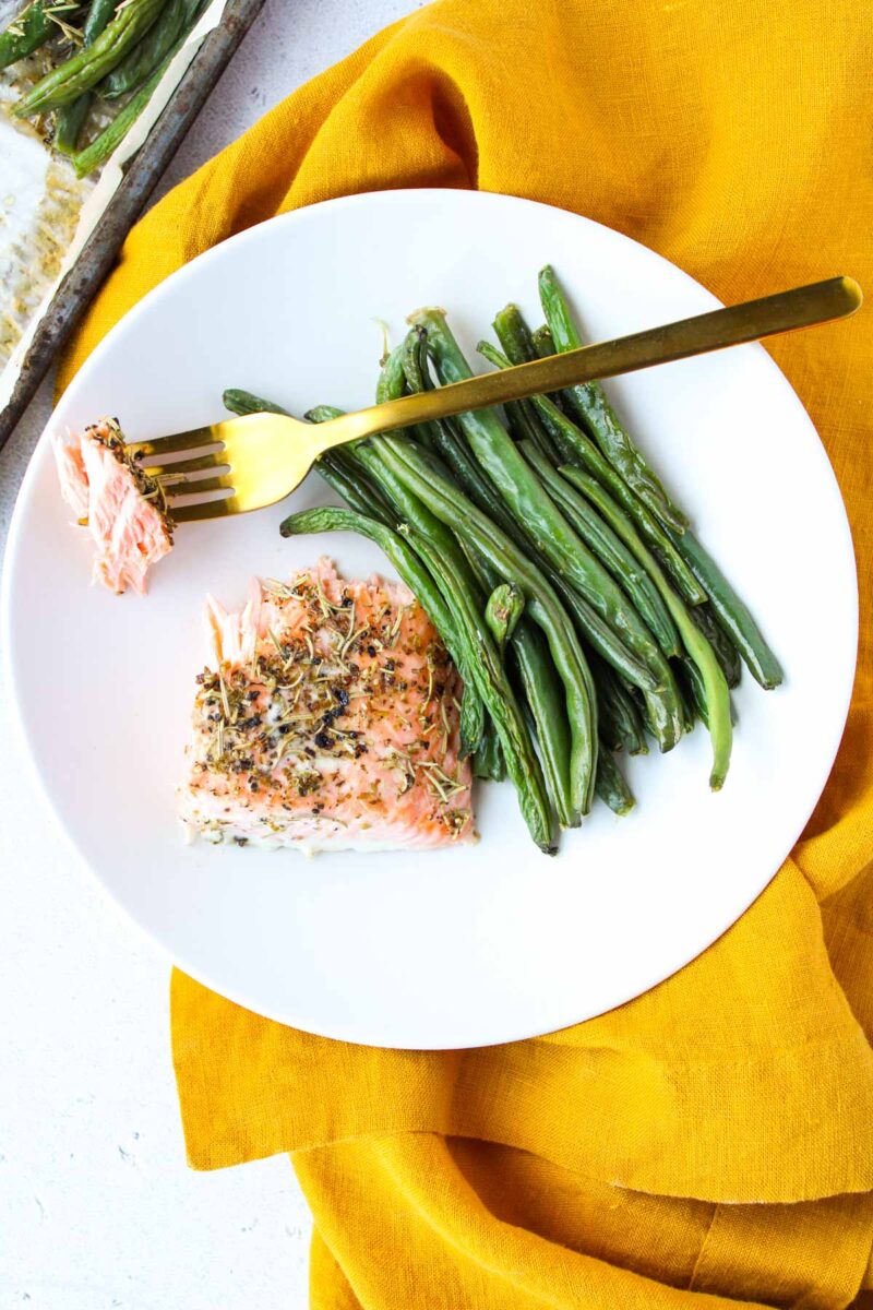 Salmon on a white plate with green beans.
