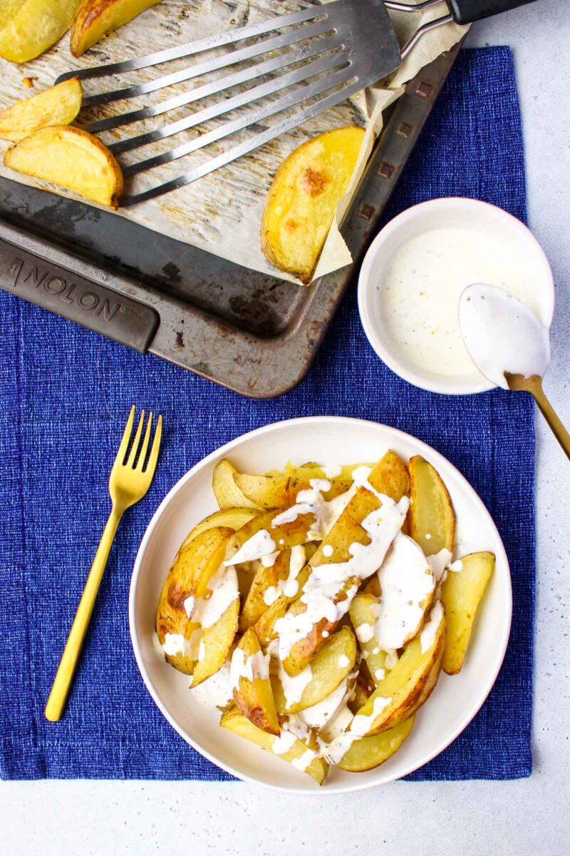 Roasted Yellow Potatoes on a white plate with a gold fork.