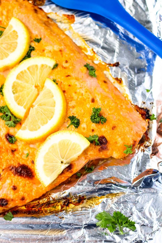 A baked salmon filet with lemon slices on top.