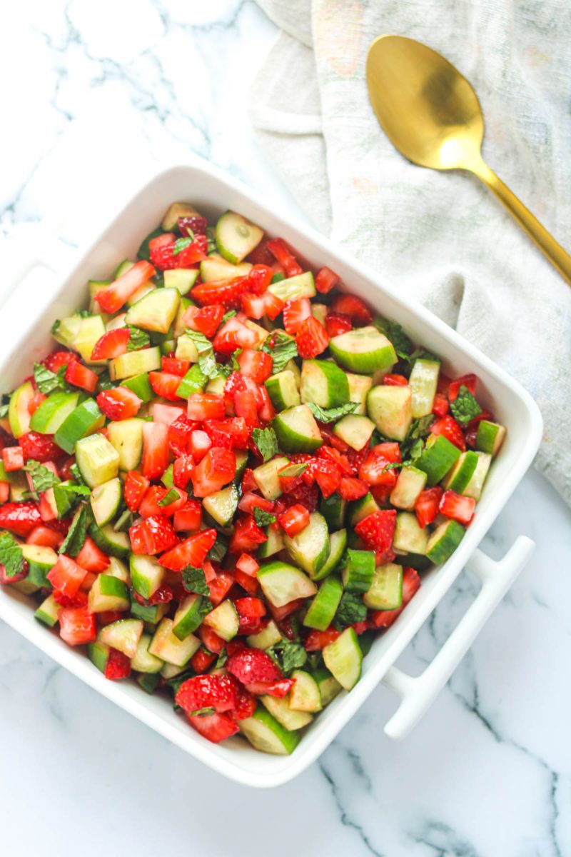 Overhead shot of Strawberry Cucumber Salad with Mint in a white serving dish on a white marble countertop