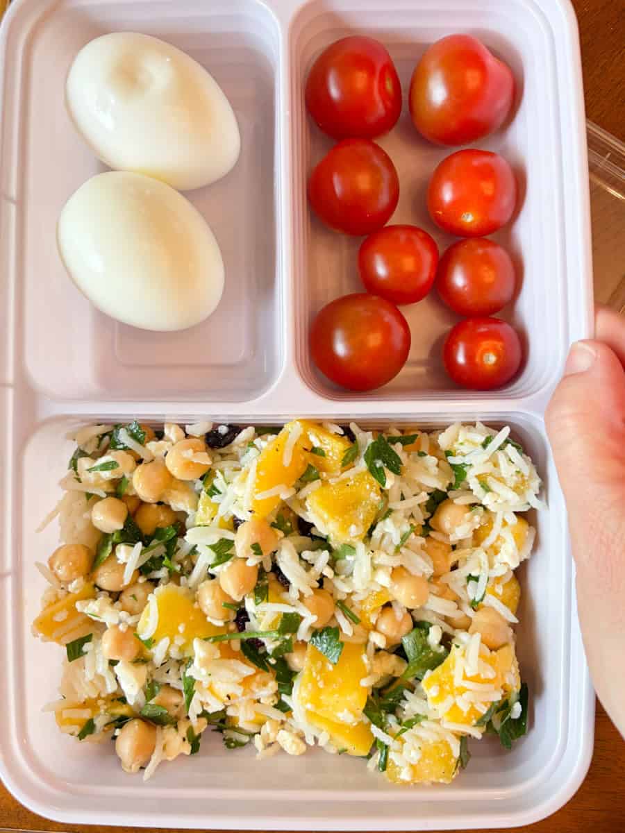 Meal prep container with rice salad, hard boiled eggs and cherry tomatoes.