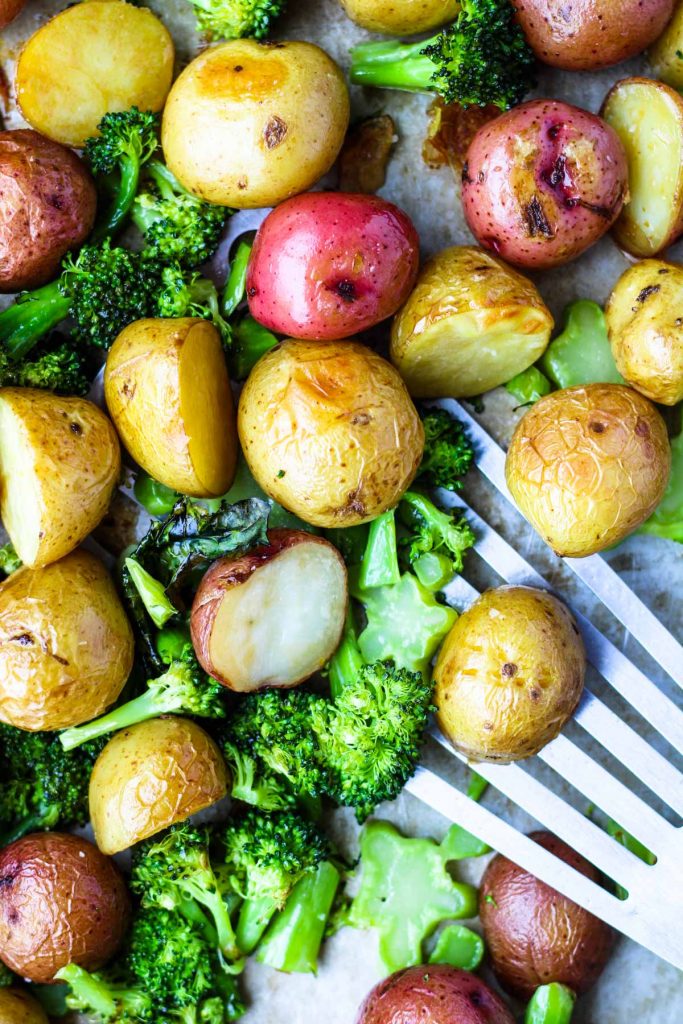 Potatoes and broccoli on a cookie sheet.