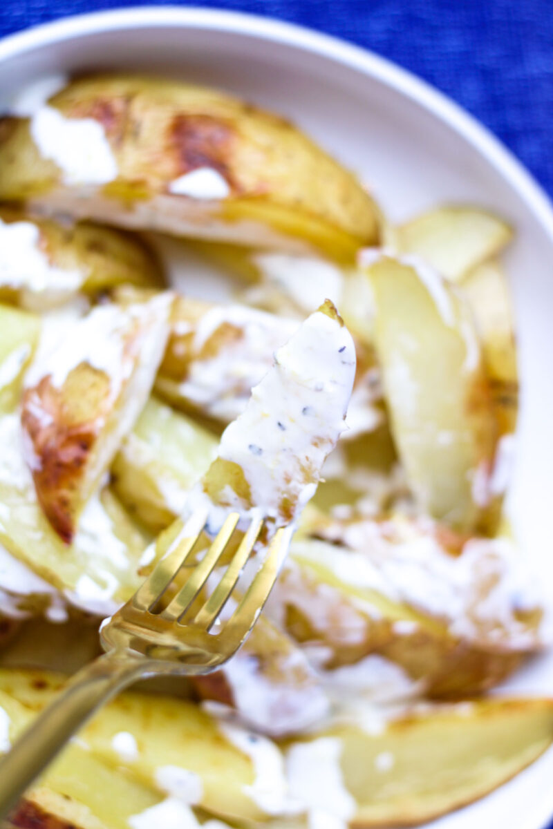 Roasted Yellow Potatoes with Greek Yogurt Sauce on a gold fork.