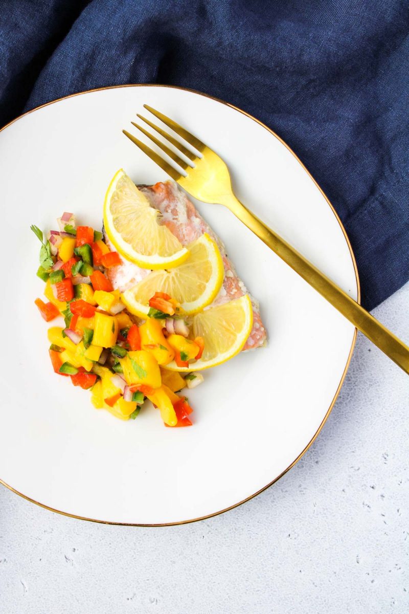 A white plate with salmon and mango salsa.