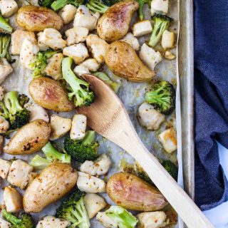 Sheet Pan with broccoli, chicken and potatoes with a wooden spoon in it