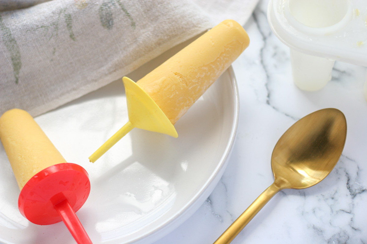 Simple 2-Ingredient Greek Yogurt Summer Popsicles on a white plate with a gold spoon beside