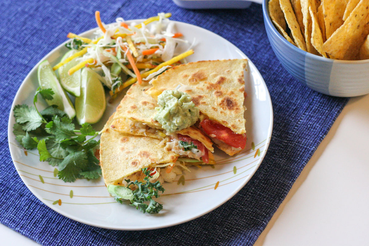 Simple Haddock Quesadillas on a white plate with lime wedges and cilantro on the side