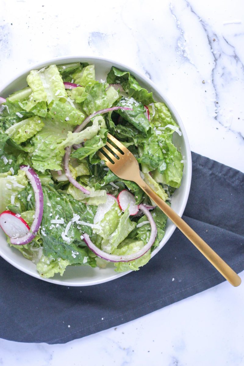 Simple Romaine Salad with Radish and Parmesan in a white plate on a marble background