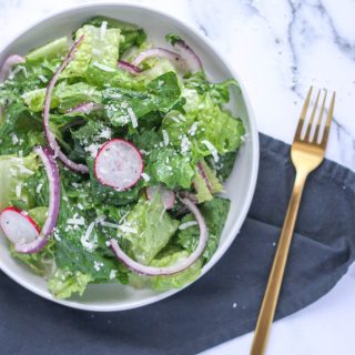 Simple Romaine Salad with Radish and Parmesan on a white plate with a gold fork