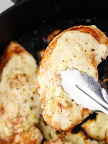 Chicken breasts with lemon greek yogurt sauce in a cast iron pan.