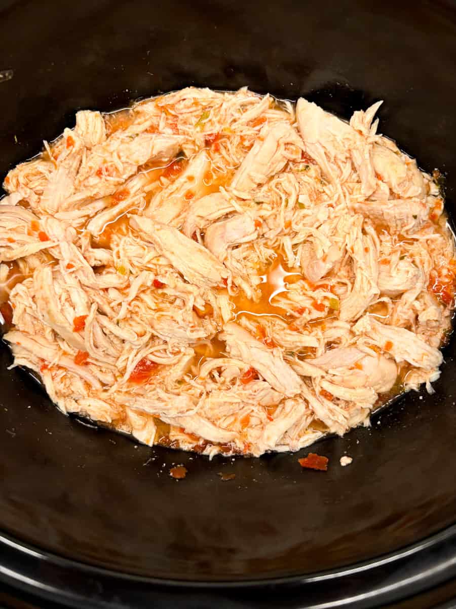 Shredded salsa chicken in a slow cooker.