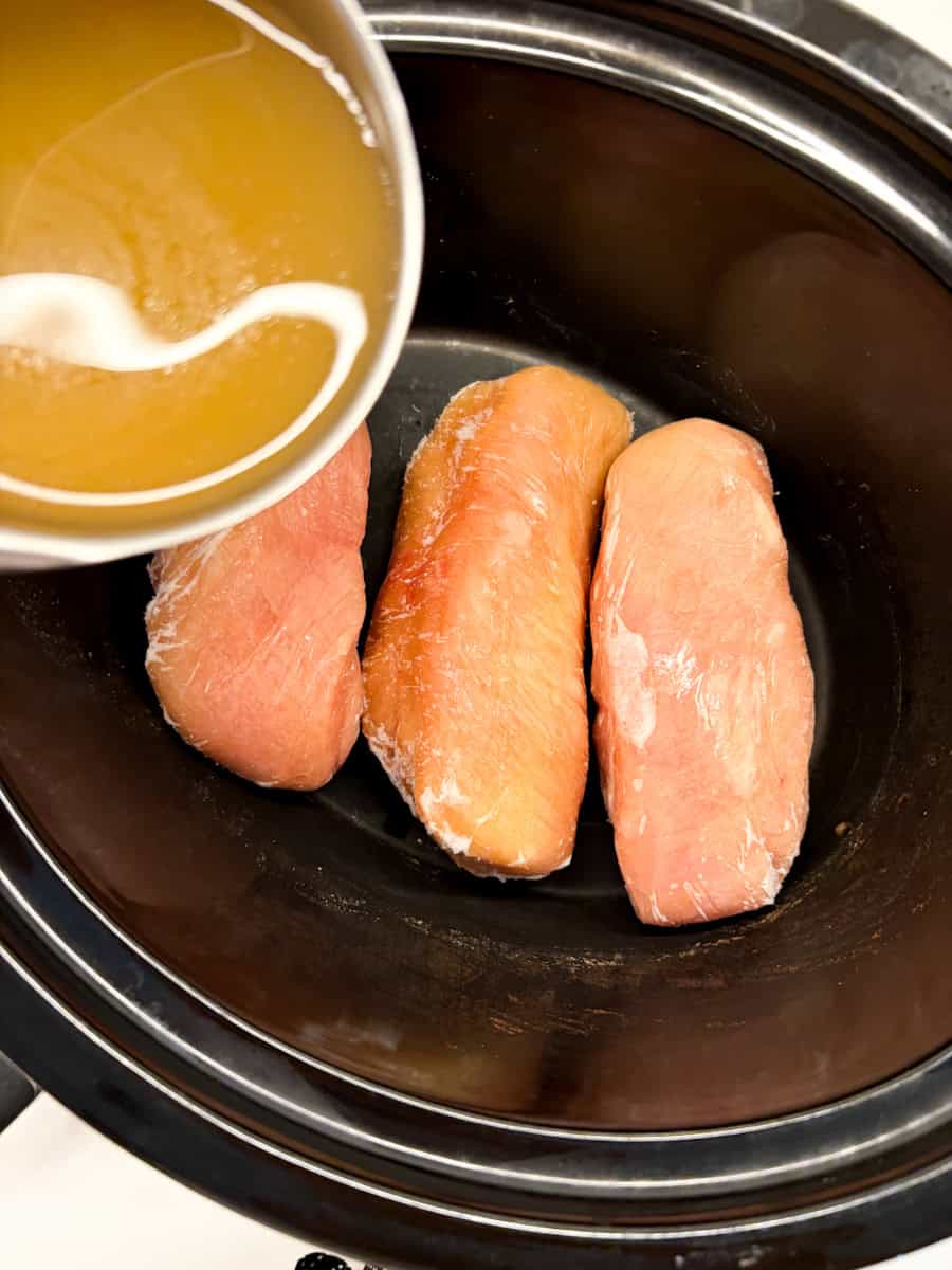 Three chicken breasts in a slow cooker.