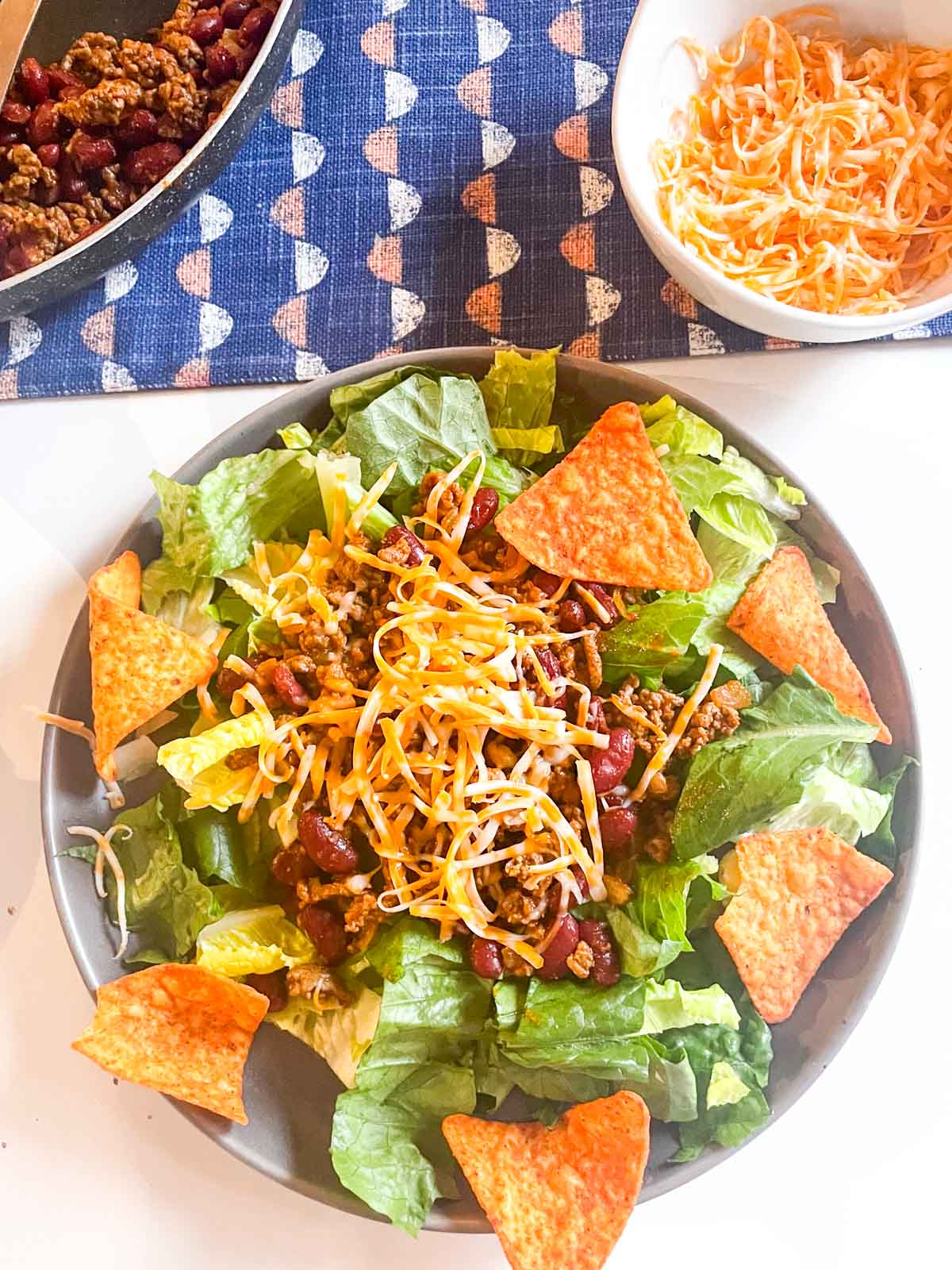 Taco salad on a plate with cheese and Doritos.
