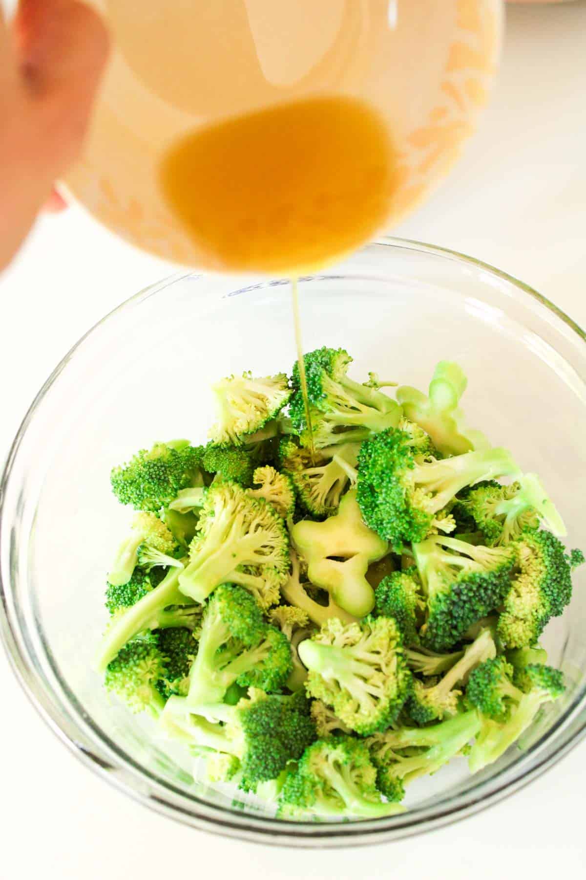 Olive oil getting drizzled over broccoli florets.