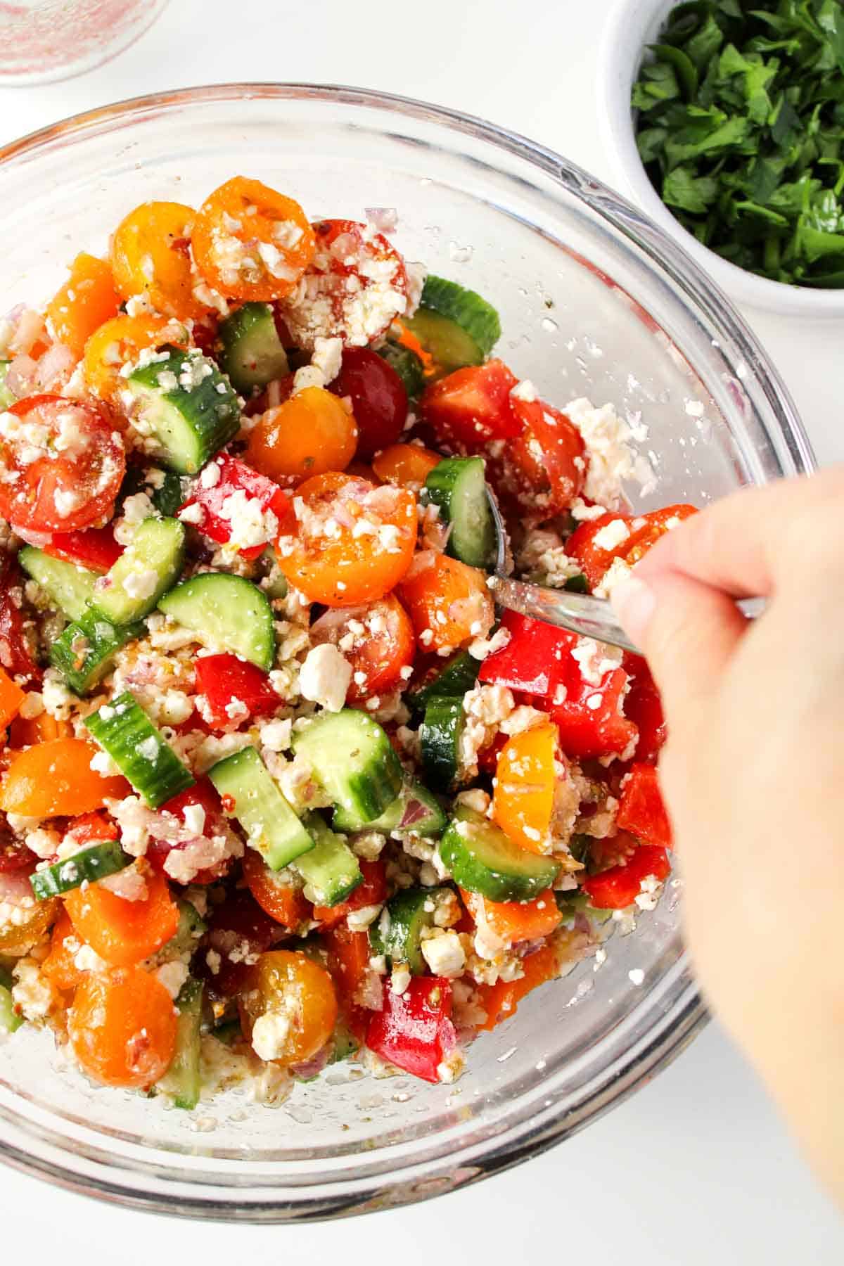 Stirring a bowl of Greek salad.