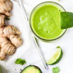 Tropical Green Smoothie with ginger root and avocado beside it