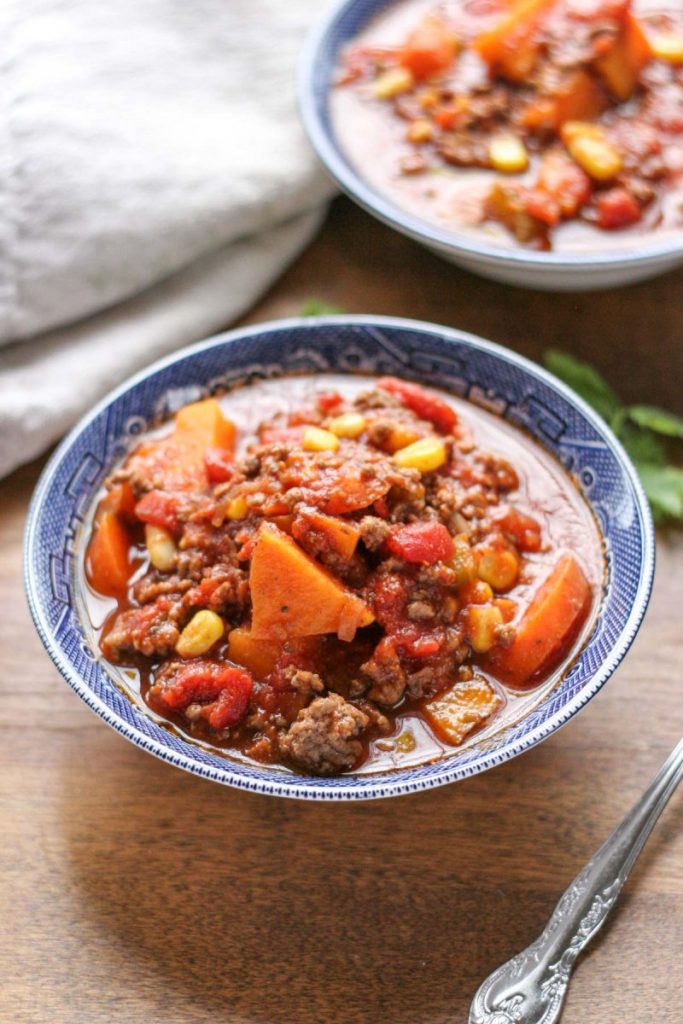 Two blue bowls filled with Easy Weeknight Hamburger Soup with Sweet Potatoes on a brown wood table