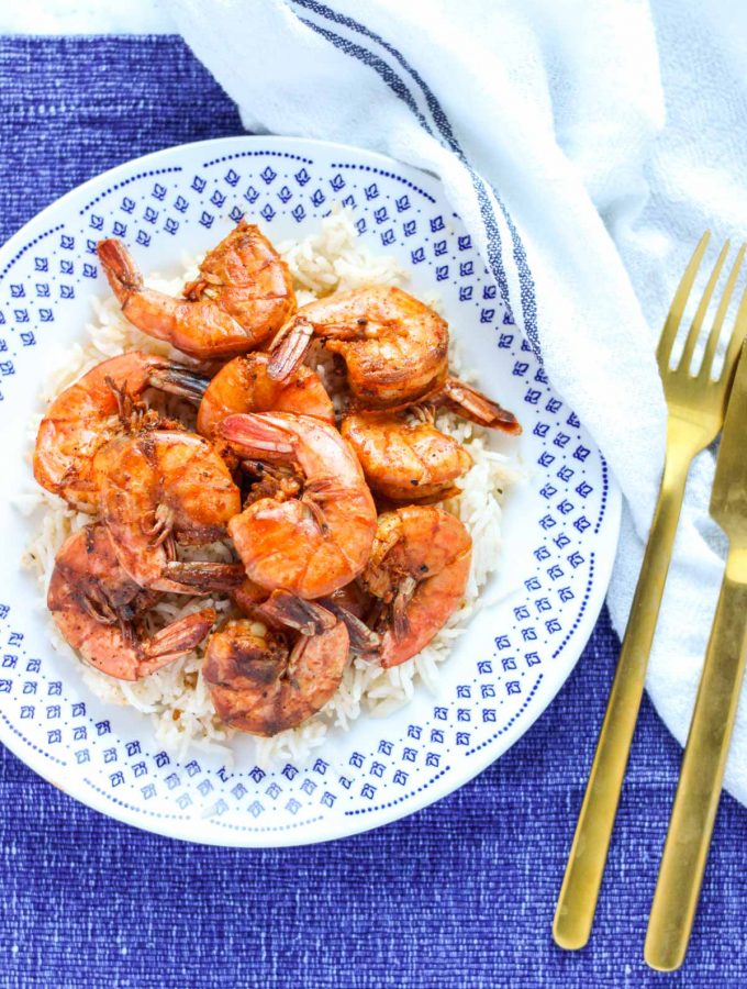 White and blue plate filled with Sweet and Spicy Shrimp on rice