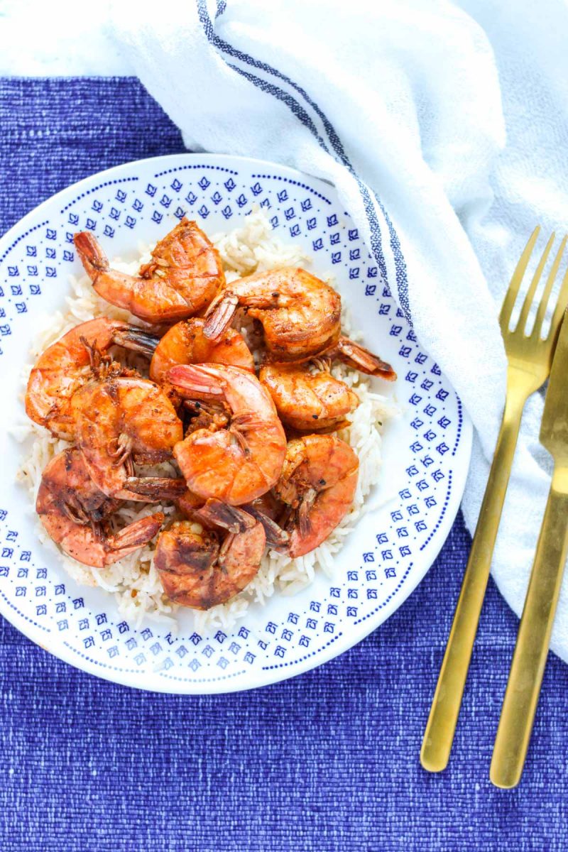 White and blue plate filled with Sweet and Spicy Shrimp on rice