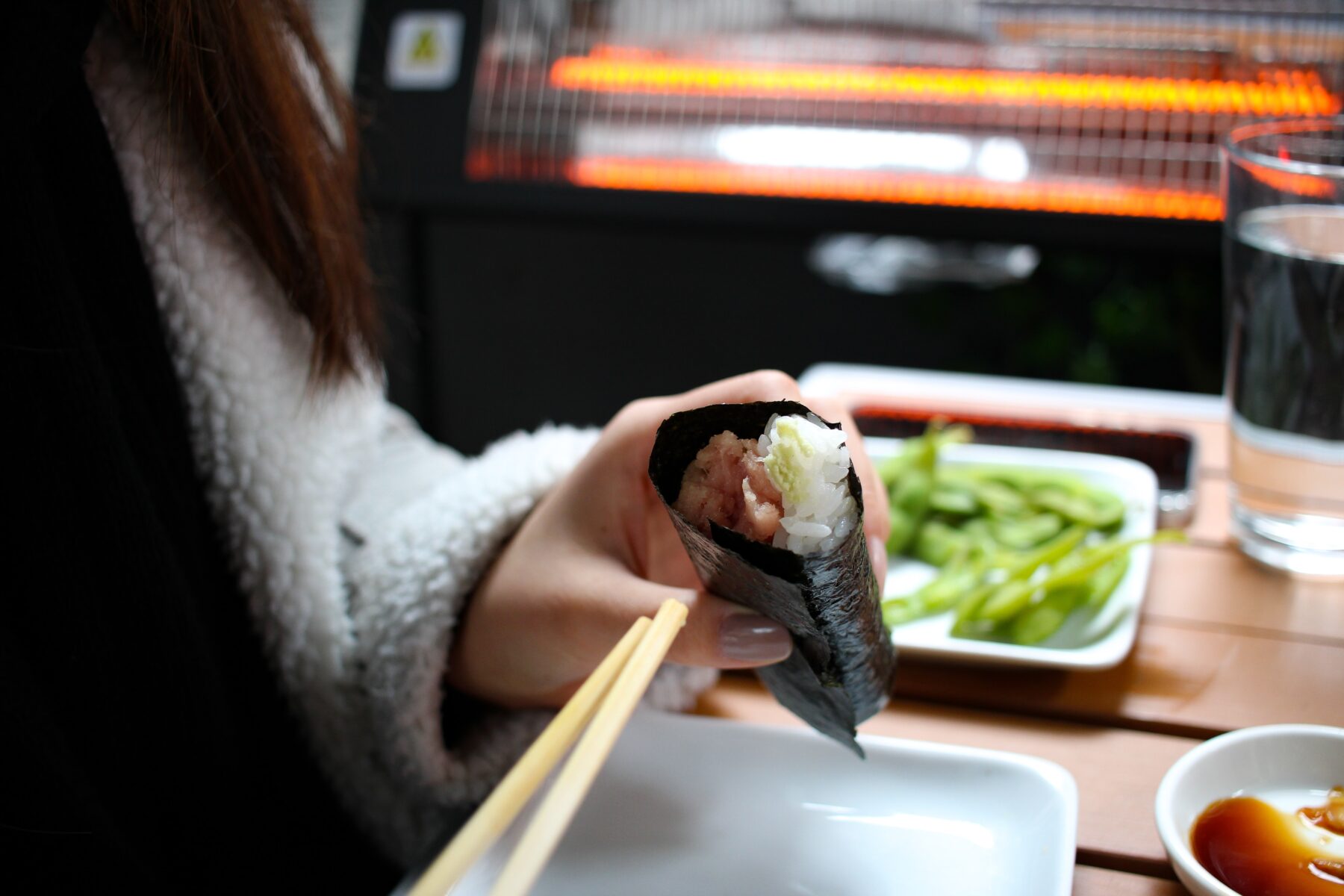 A woman holding a sushi roll.