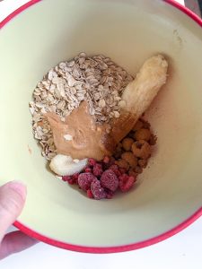 a bowl with oats, banana, peanut butter, raspberries and cinnamon