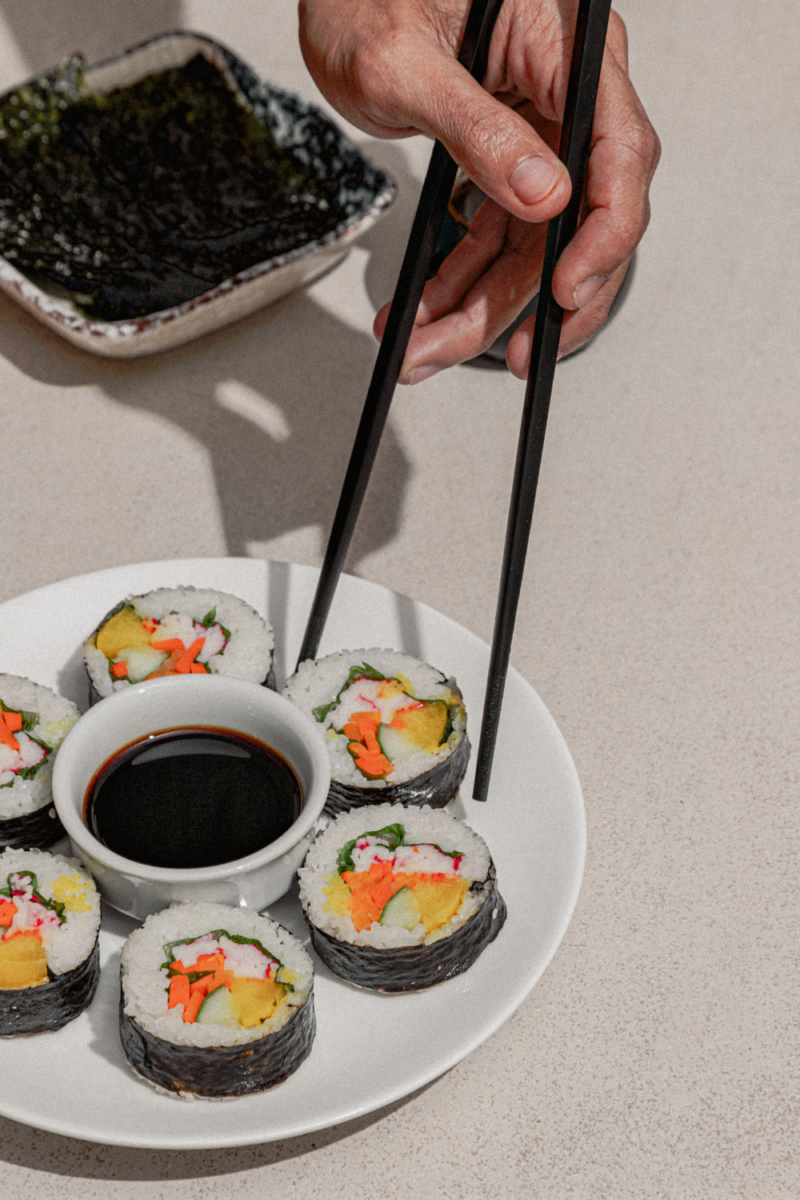 A plate of sushi rolls and chopsticks.